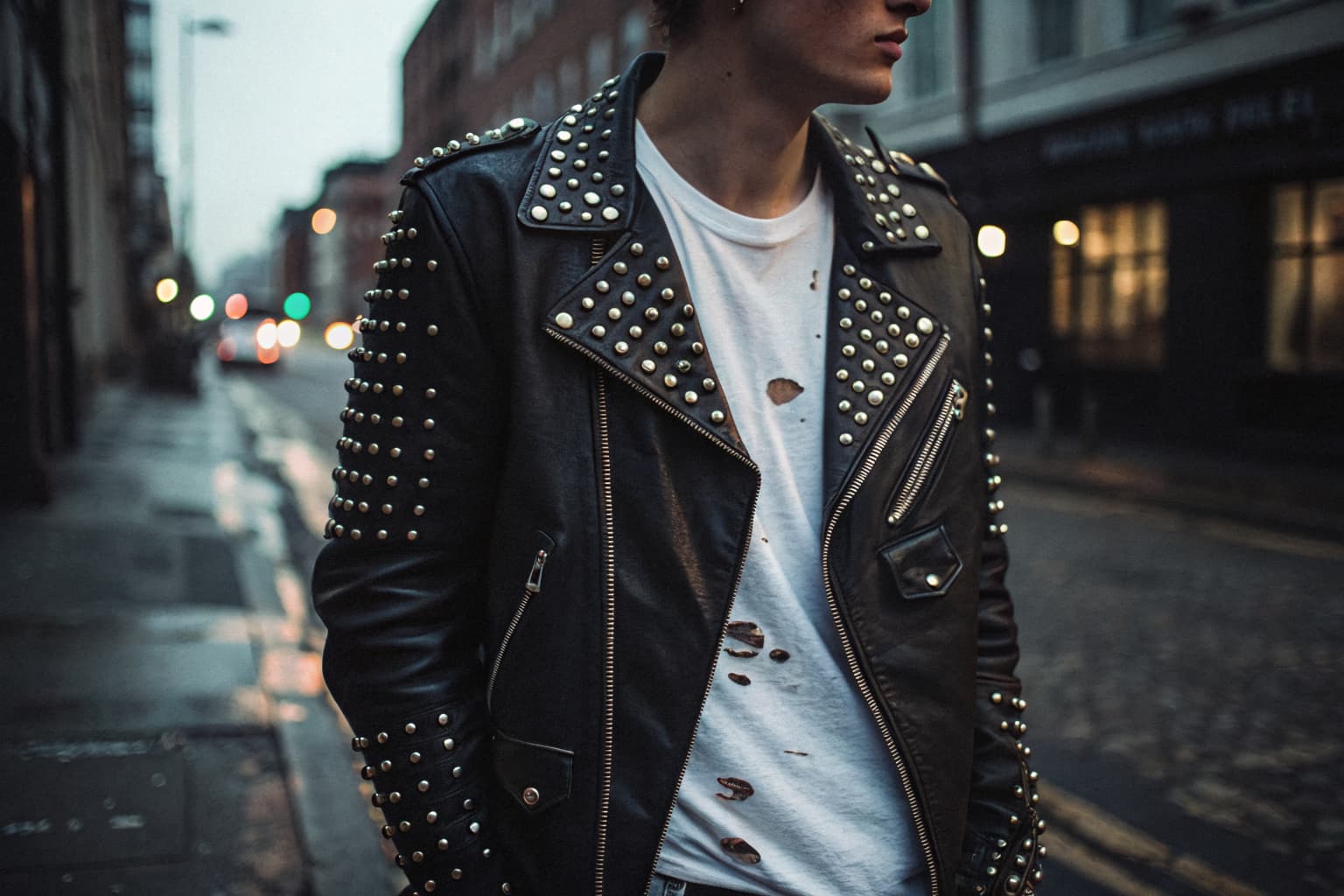 Iconic punk street fashion: black leather jacket with safety pins and studs over a ripped t-shirt